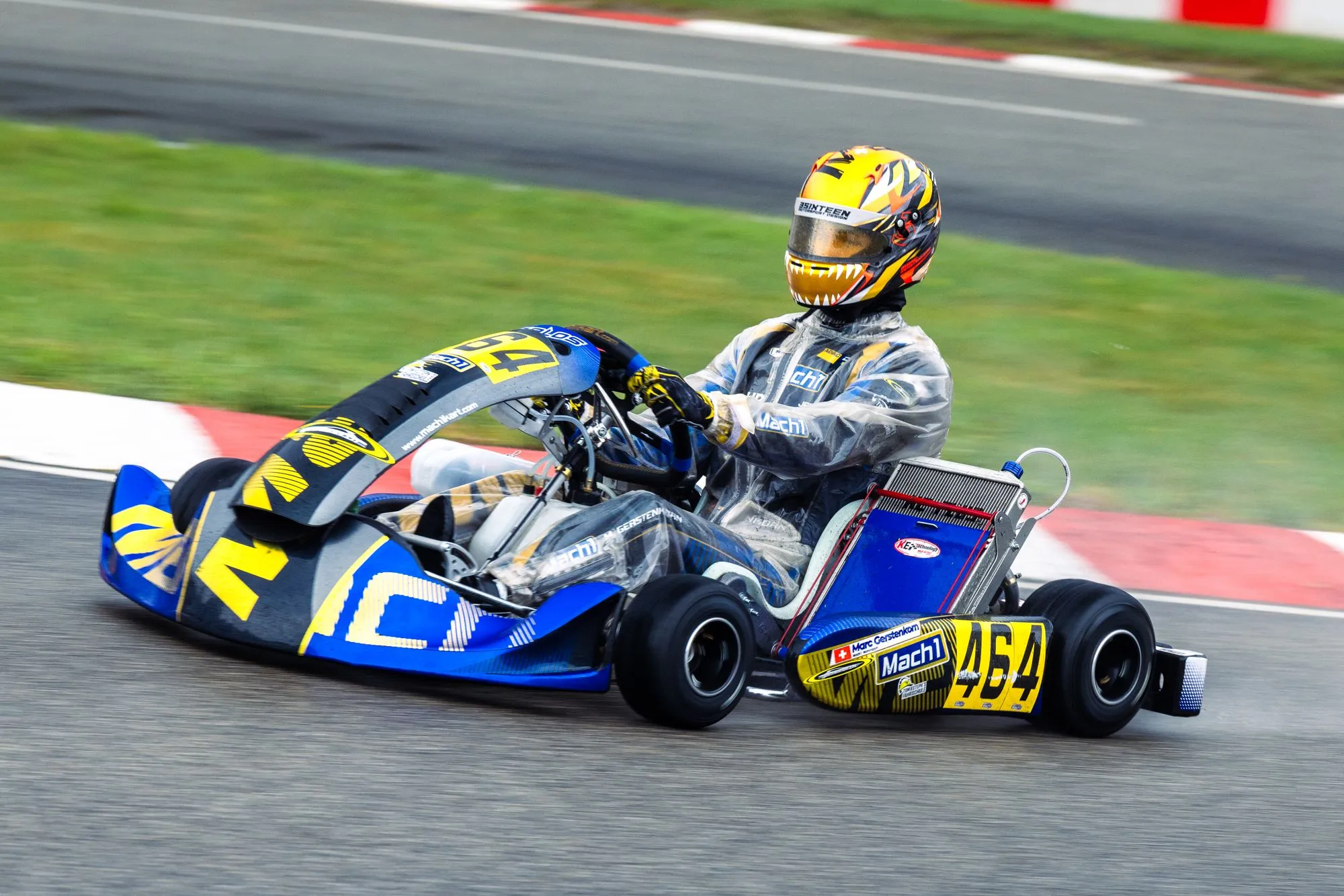 Mach1 Rennkart mit Fahrer im gelben Helm in der Kurve bei der Deutschen Kart-Meisterschaft in Ampfing