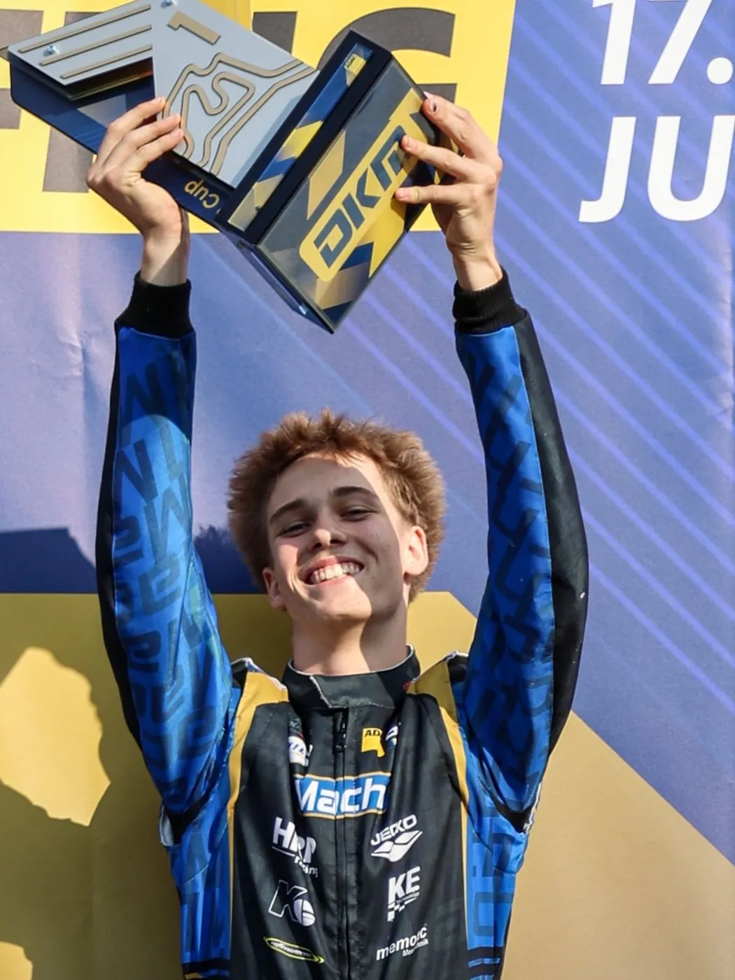 Mach1 Fahrer jubelt mit der Siegertrophäe der Deutschen Kart-Meisterschaft